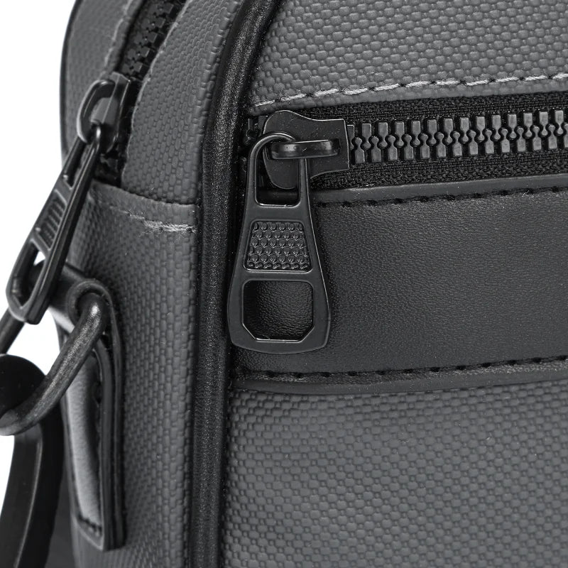 Primer plano de un bolso cruz de cuero sintético negro con bolsillo con cremallera y correa ajustable.
