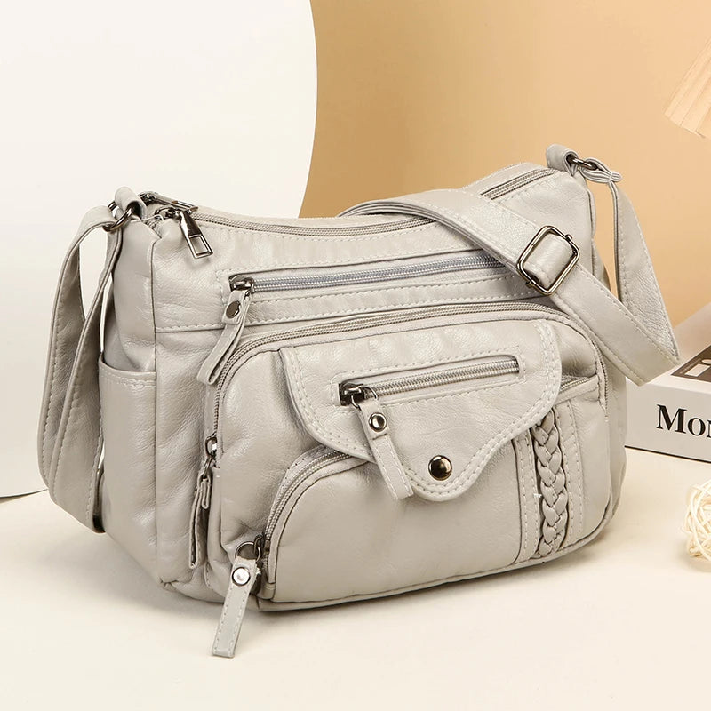 A light gray luxury leather tote bag with silver hardware and a quilted texture is shown against a beige background.