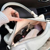 A close-up of a white PU leather crossbody shoulder bag with silver hardware resting on a dark car seat.