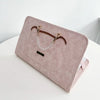 A pink faux leather laptop sleeve with a leather strap and silver chain detail resting on a white surface.