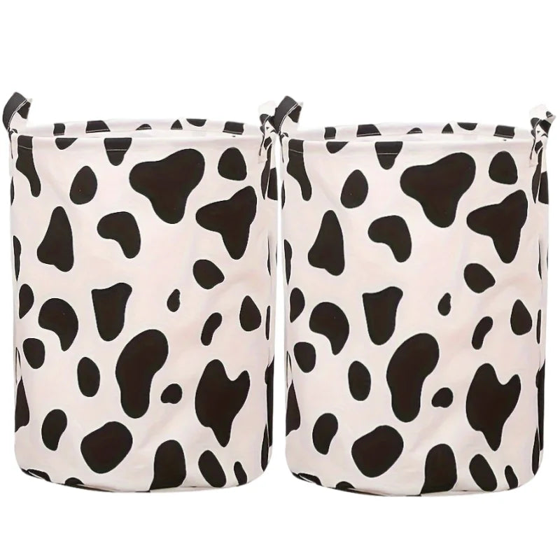 Un ensemble de paniers à linge en tissu blanc avec un motif vache noire.
