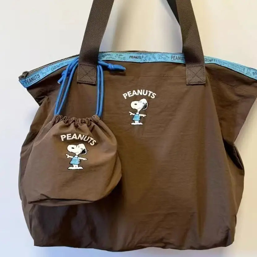 A brown canvas shoulder bag featuring a Snoopy cartoon design and blue trim.
