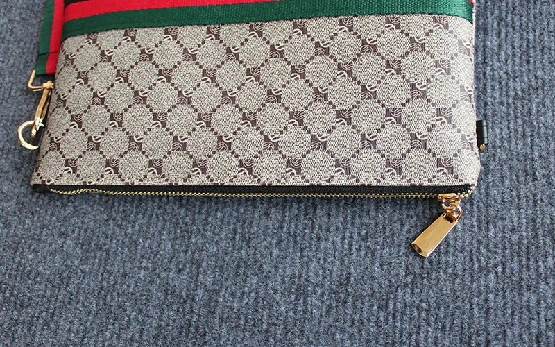 Beige Gucci Monogramm-Clutch mit grün-rotem Zierrand auf grauem Stoff