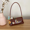 A brown acrylic chain strap handbag with multi-colored beads resting on a wooden surface.