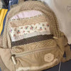 A beige backpack featuring layered fabric panels with floral and checkered patterns.