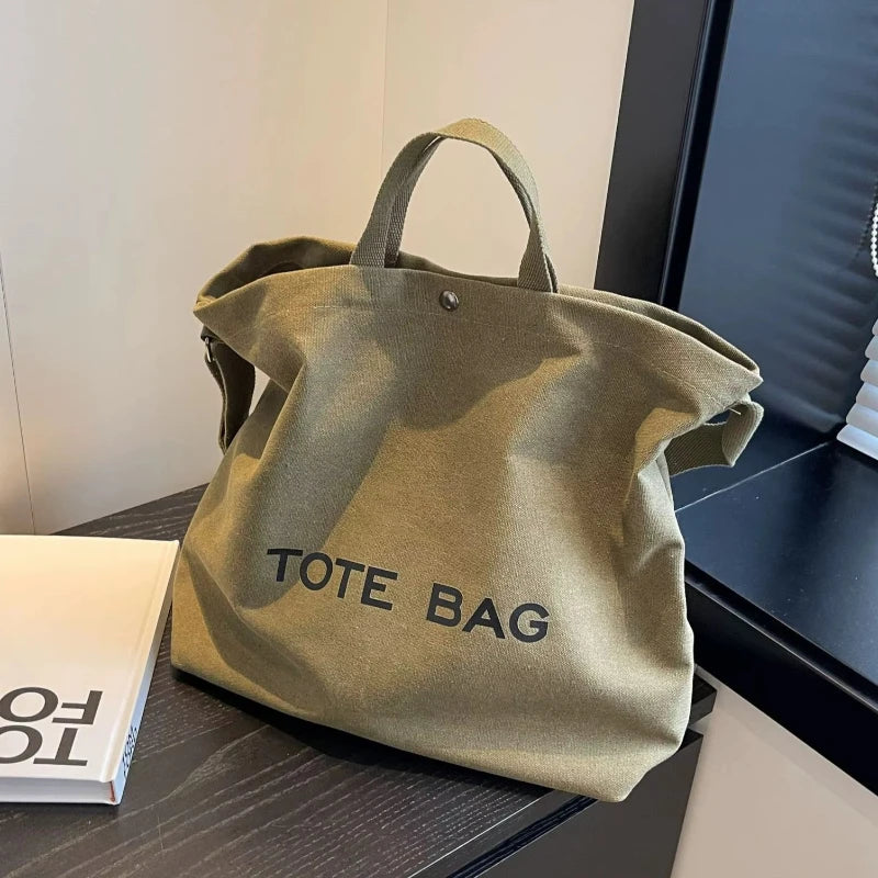 A khaki canvas tote bag with handles is displayed on a dark surface.
