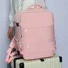 A pink compact travel backpack resting on top of a white suitcase.
