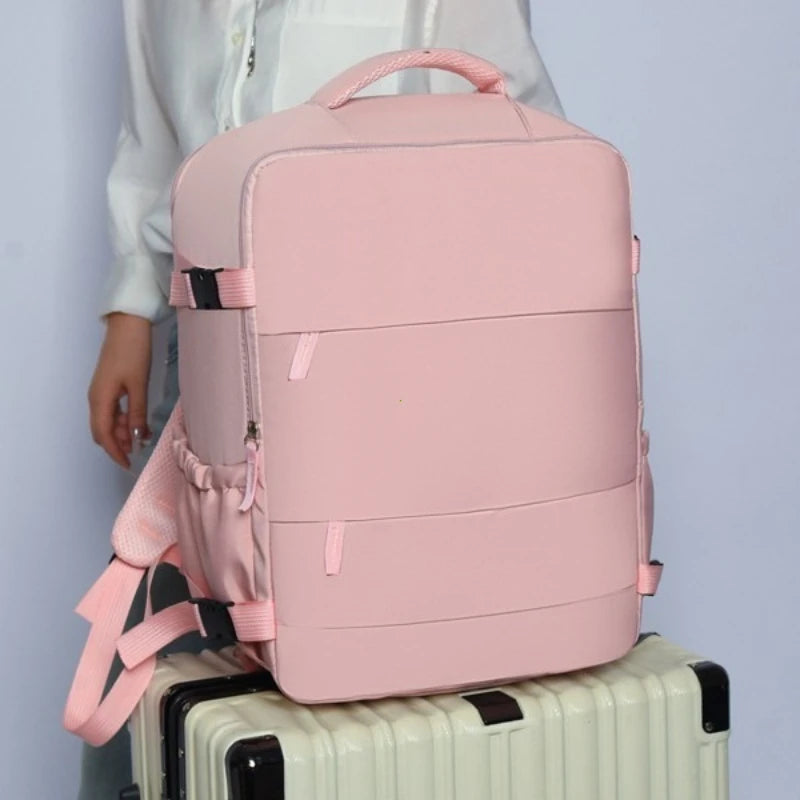 A pink compact travel backpack resting on top of a white suitcase.