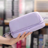Une trousse à crayons violette de grande capacité à plusieurs compartiments tenue par une main.