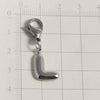 Silver stainless steel alphabet letter charm with a lobster clasp placed on a ruler.