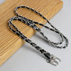 A silver and black leather chain strap is displayed on a wooden surface.
