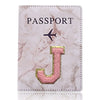 Portafolio de pasaporte de cuero marmolado rosa con una J dorada grabada en la parte delantera.