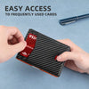 A hand holds a black patterned leather card wallet displaying various cards, with a pen visible in the background.