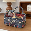 A dark floral quilted fabric storage basket holding a glass bottle, resting on a wooden surface.
