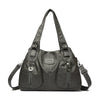 Schwarze Vintage-Handtasche aus weichem Kunstleder mit Klappverschluss und Lederverzierung.
