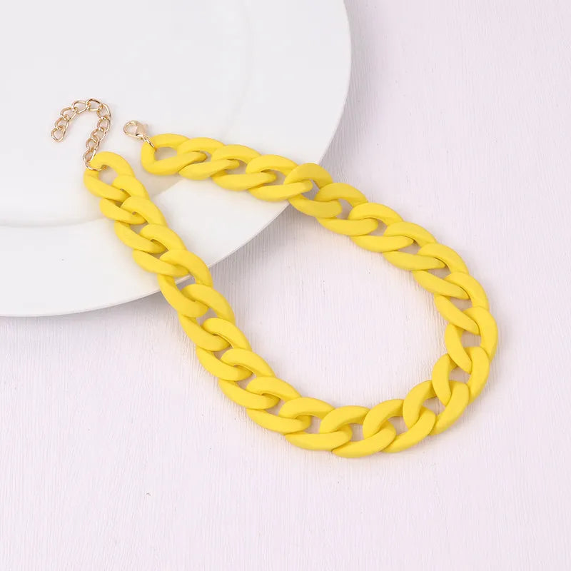 A yellow acrylic statement chain necklace with a gold-colored clasp is displayed on a white background.