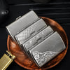 A silver metal cigarette case is shown open, resting on a wooden tray next to a gold-colored lighter.