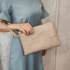 Una persona vistiendo un vestido azul claro sostiene un bolso de cuero PU con estampado floral beige.