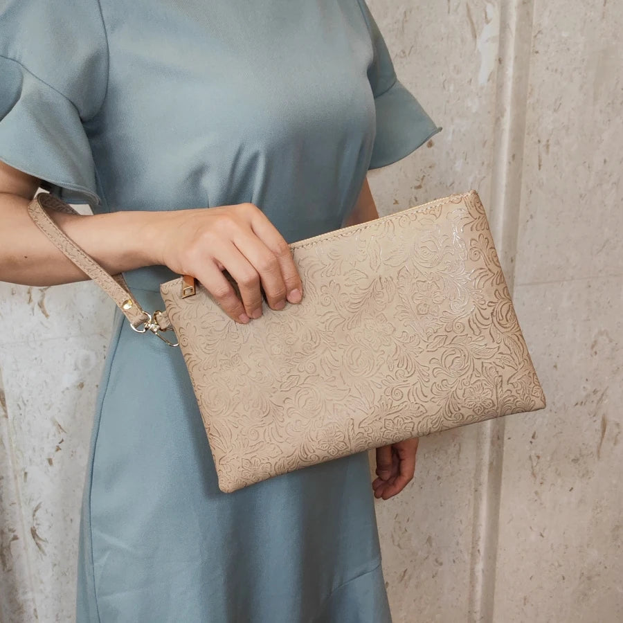 Una persona vistiendo un vestido azul claro sostiene un bolso de cuero PU con estampado floral beige.