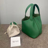 A deep green leather bucket bag next to a light beige fabric pouch and a card labeled MENDY.