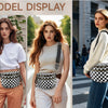 Model trägt eine karierte Crossbody-Tasche und weißes Oberteil, posiert im Freien.