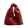 A deep red leather minimalist crossbody tote bag folded and displayed on a white background.
