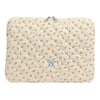 Funda acolchada para portátil de color crema con estampado floral amarillo.