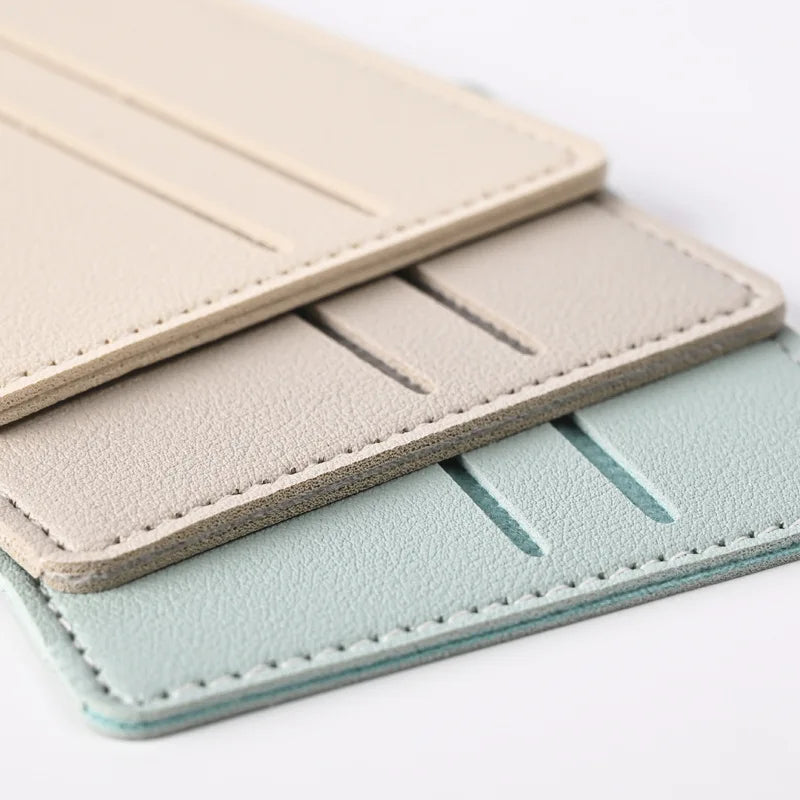 Tres porta tarjetas de cuero PU apilados en colores beige, gris claro y verde menta.