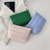 Three quilted cosmetic travel bags in shades of green, blue, and pink are displayed on a white surface.
