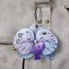 A realistic purple and blue phalaenopsis orchid flower keychain attached to a gray leather bag.
