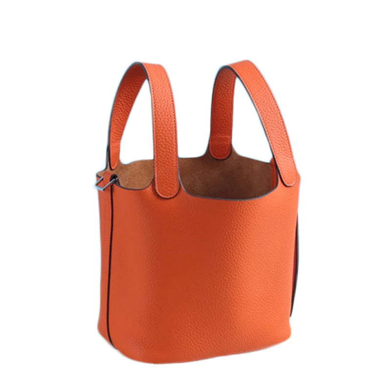Orangefarbige, echte Leder-Bucketbag mit brauner Futter und Ledergriffen.