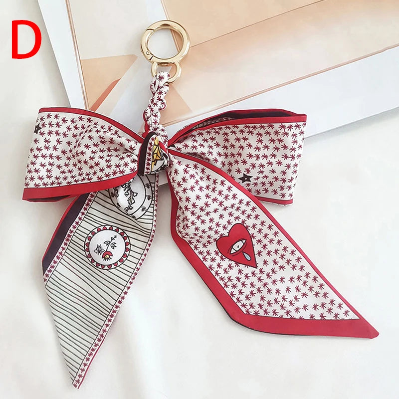 Llavero de lazo de seda estampado en rojo y blanco con anillo de oro.