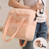 A light pink double-layer insulated lunch bag with tan straps being held by a person.