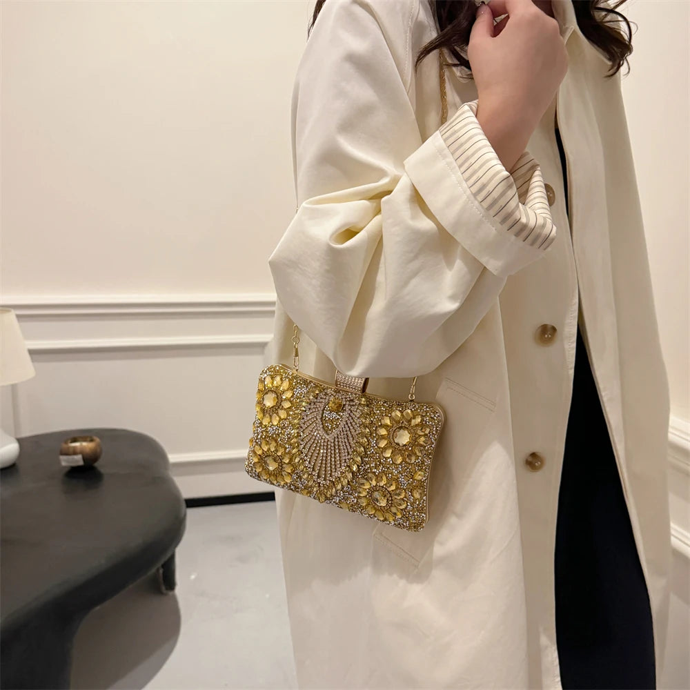 A woman wearing a cream-colored coat is holding a gold rhinestone evening clutch bag.