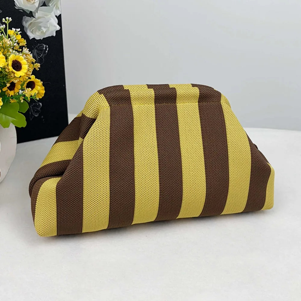 A beige and brown striped knit cloud makeup bag resting on a white surface.