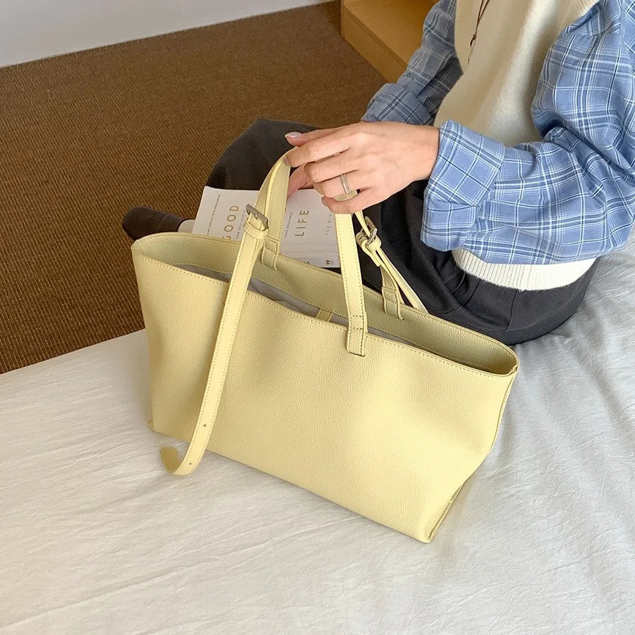 Une personne tient un sac à main en cuir PU jaune clair et décontracté sur une surface blanche.