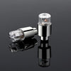 A pair of chrome LED tire valve stem lights, one in its housing and the other as a separate component.