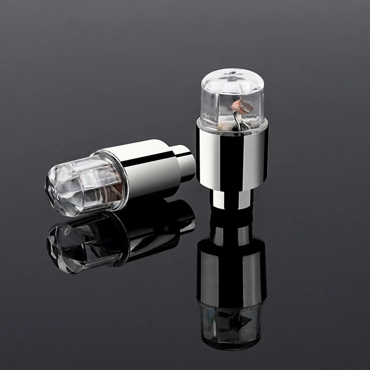 A pair of chrome LED tire valve stem lights, one in its housing and the other as a separate component.