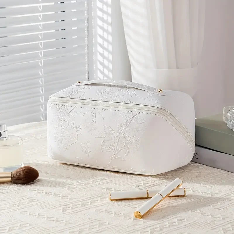 A white vintage floral waterproof makeup tote bag resting on a light surface next to a cosmetic brush and a white applicator.