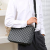 A man wearing a white shirt holds a gray plaid crossbody shoulder bag with black strap.