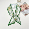 Foulard de cheveux en soie floral vert et blanc noué en nœud, à côté de sous-vêtements blancs.