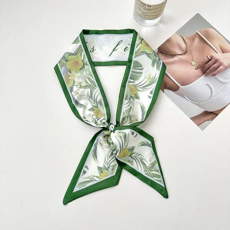 Foulard de cheveux en soie floral vert et blanc noué en nœud, à côté de sous-vêtements blancs.