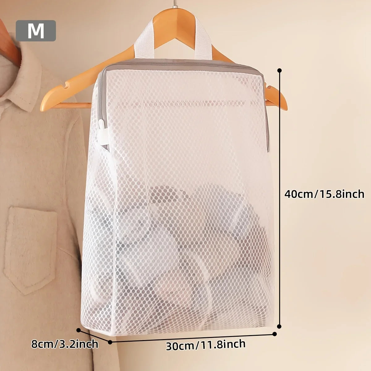 A white honeycomb mesh laundry bag is shown hanging on a wooden hanger against a light background.