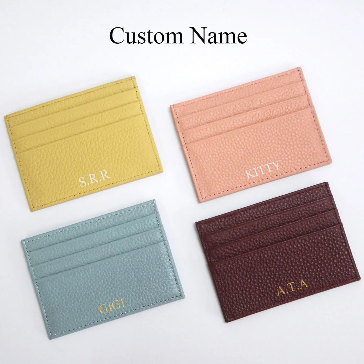 Four personalized genuine leather card holders in yellow, pink, blue-green, and maroon.