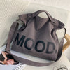 A gray canvas tote bag featuring the word MOOD in large black lettering, resting on a white surface.