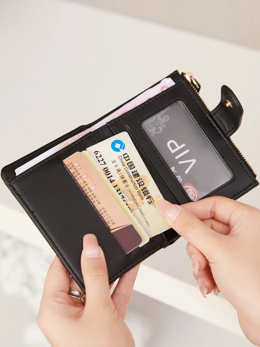 A hand is opening a black PU leather bifold wallet with an ID window, showing several credit cards inside.