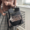 A black leopard print fashion backpack is displayed next to a person wearing a brown sweater and plaid skirt.