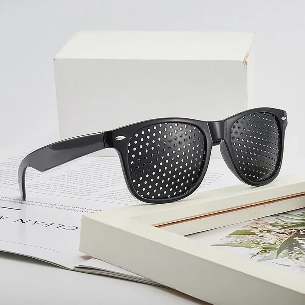 A pair of black precision vision correction glasses resting on a white box and open book.