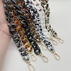 A collection of multicolor acrylic chain bracelets featuring black, white, and amber marbled patterns.