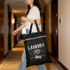 A woman walks down a hallway carrying a black laundry bag.